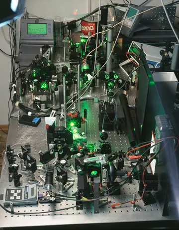 Laser optics, mirrors, cables and mounts arranged on a laboratory optical table.