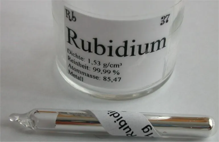 Silvery rubidium metal sealed inside a clear glass ampoule.