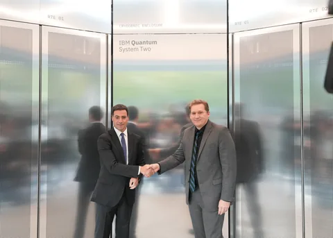Two men shake hands in front of the reflective IBM Quantum System Two enclosure at Ikerbasque.