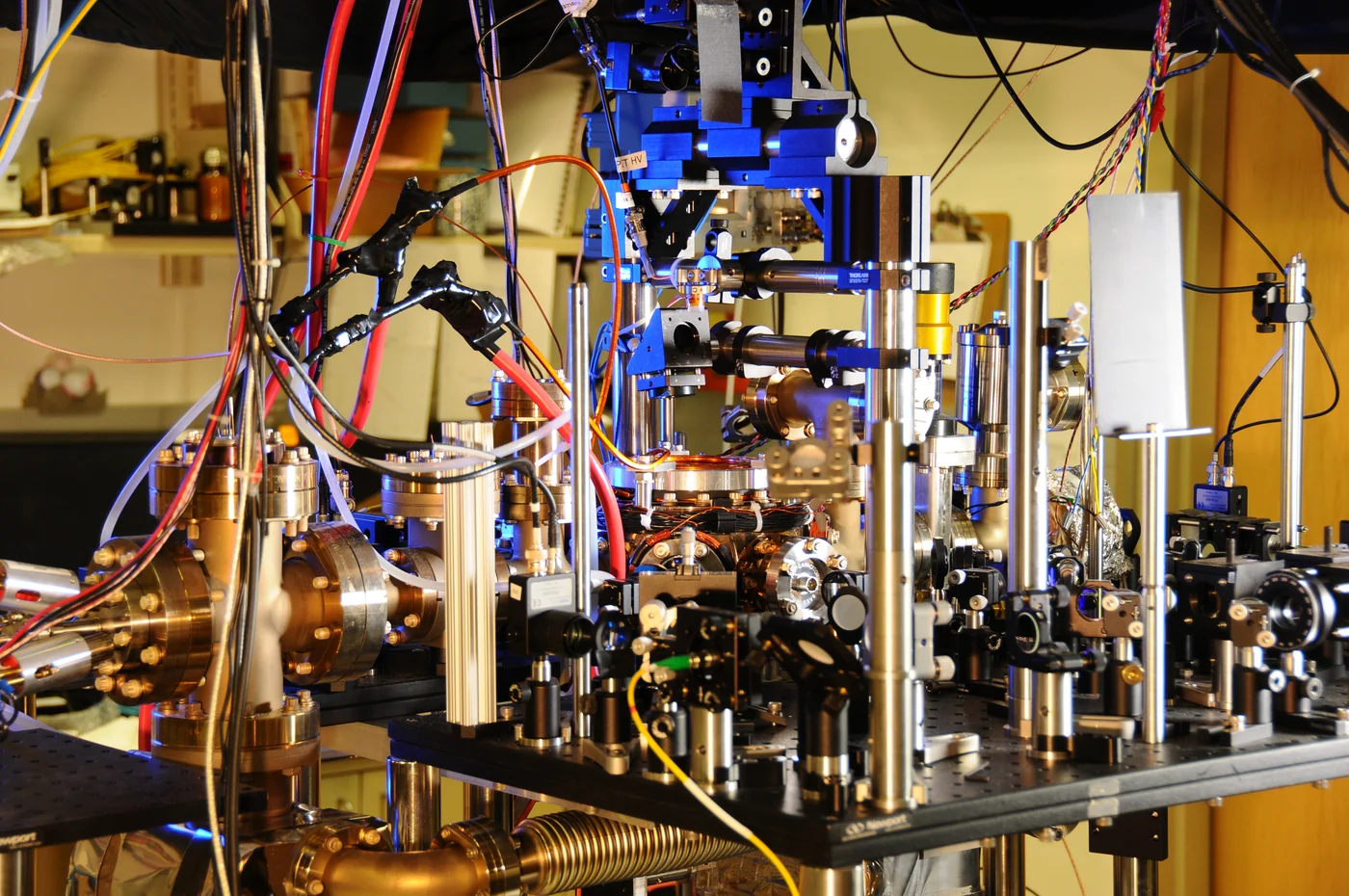 An atomic-clock laboratory apparatus with optical components, metal mounts and colored cables.