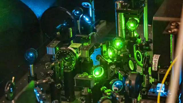 Mirrors and lenses route green laser beams across an Oak Ridge quantum-research optical bench.