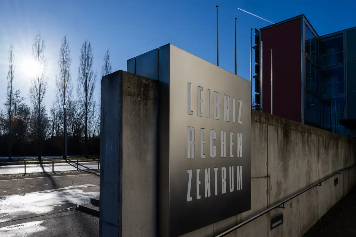 A sign reading Leibniz Rechenzentrum beside the building entrance, bare trees and winter sunlight.