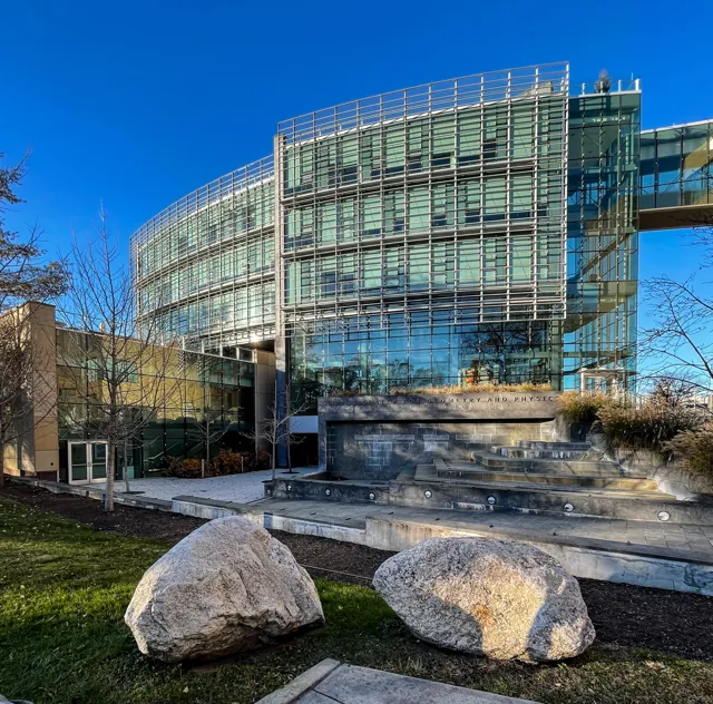 The glass facade and stone entrance of the Simons Center for Geometry and Physics.