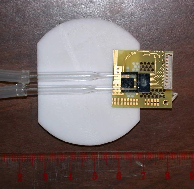 A miniature magnetic-sensing prototype and fluid channel beside a ruler.