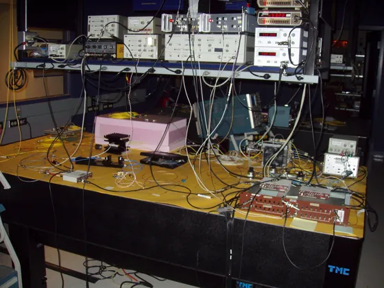 An optical table and instrument shelf form the historical Bob node in BBN’s quantum-network laboratory.
