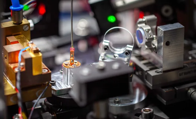 Close view of optical mounts, a glowing red diamond and components of Fraunhofer IAF’s laser-threshold magnetometer.
