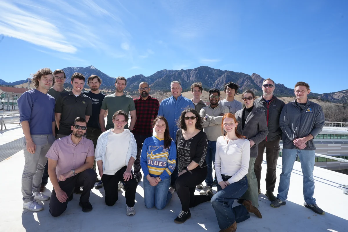 A research group posing outdoors in front of mountains in Boulder.